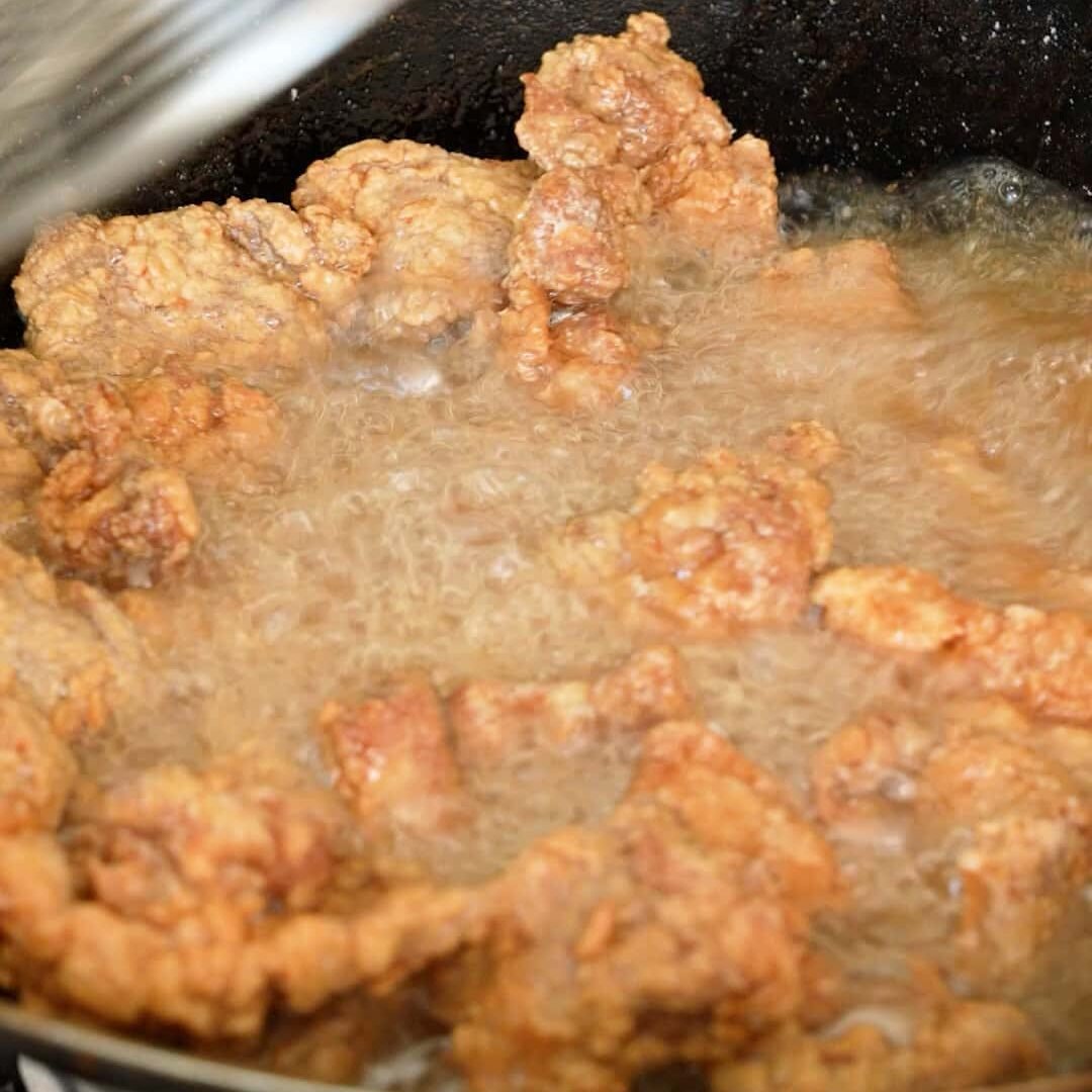 Pork pieces double frying in oil in a wok.