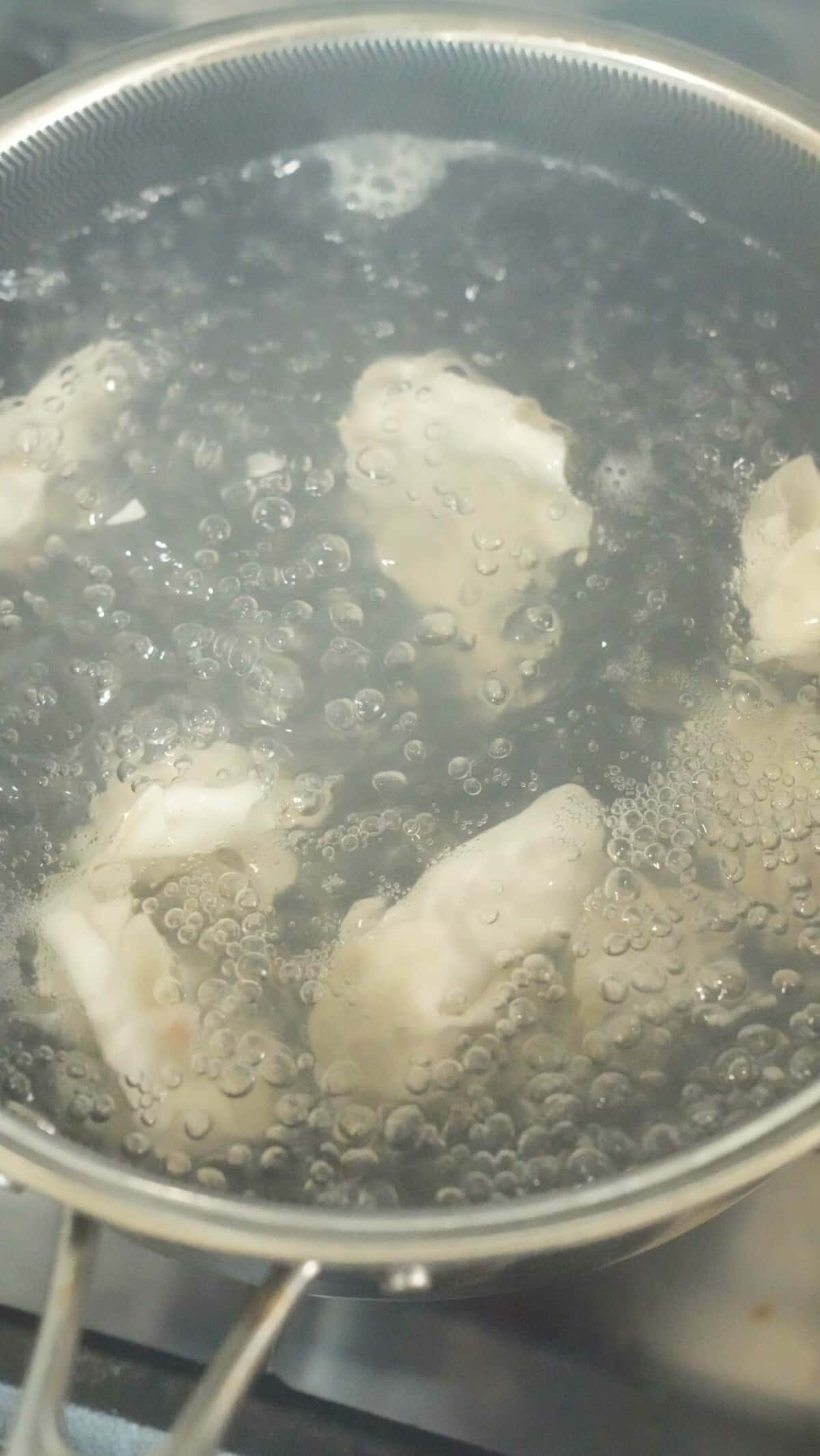 Wontons boiling in a pot of water.