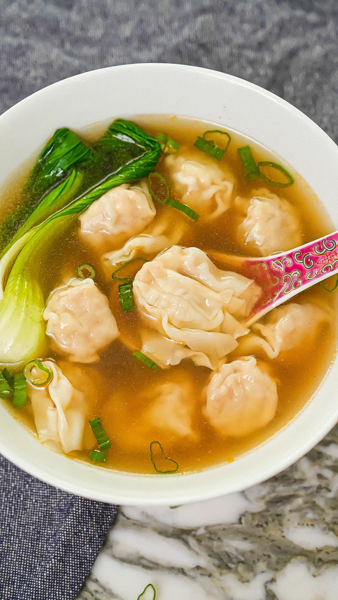 A bowl of authentic easy wonton soup with bok choy and wontons.