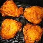 Cooked air fryer chicken thighs with crispy skin in the air fryer basket.