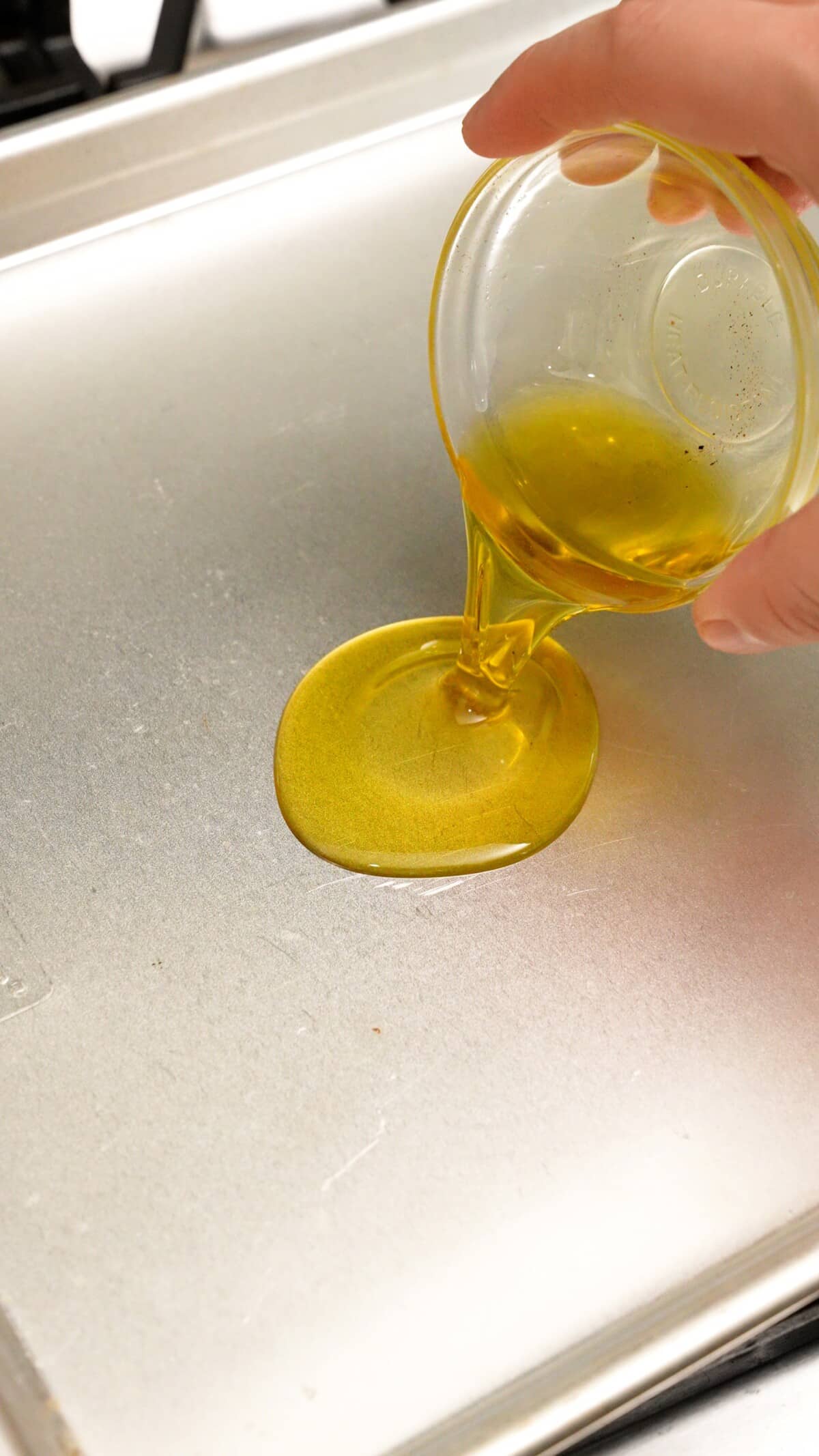 Pouring olive oil on a preheated baking sheet.