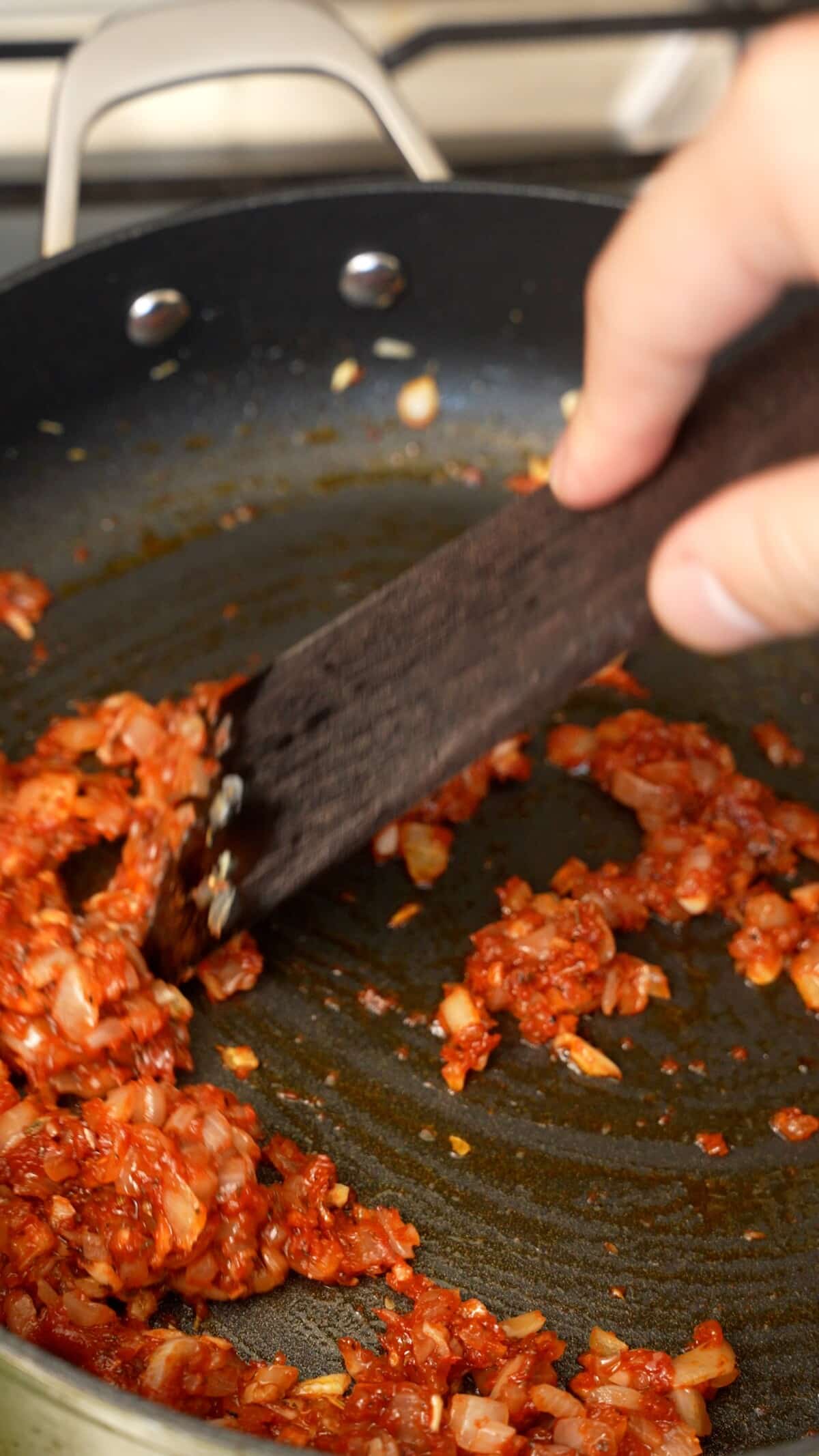 Cooking tomato paste with onions and garlic in a pan.