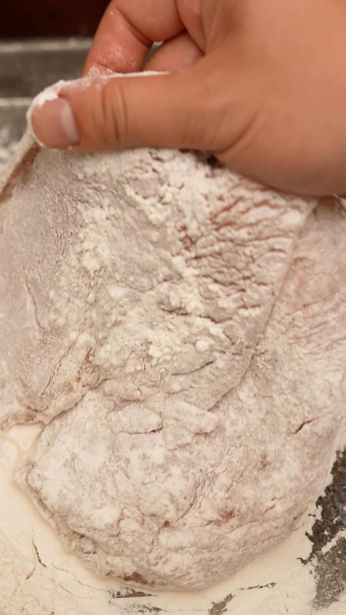 Dredging a chicken cutlet in flour.