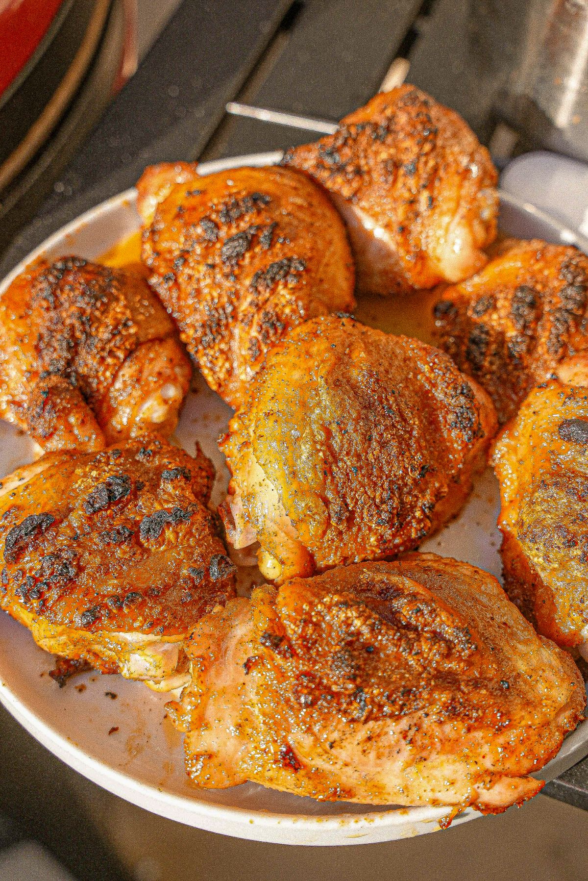 A plate of grilled chicken thighs with crispy skin and grill marks.