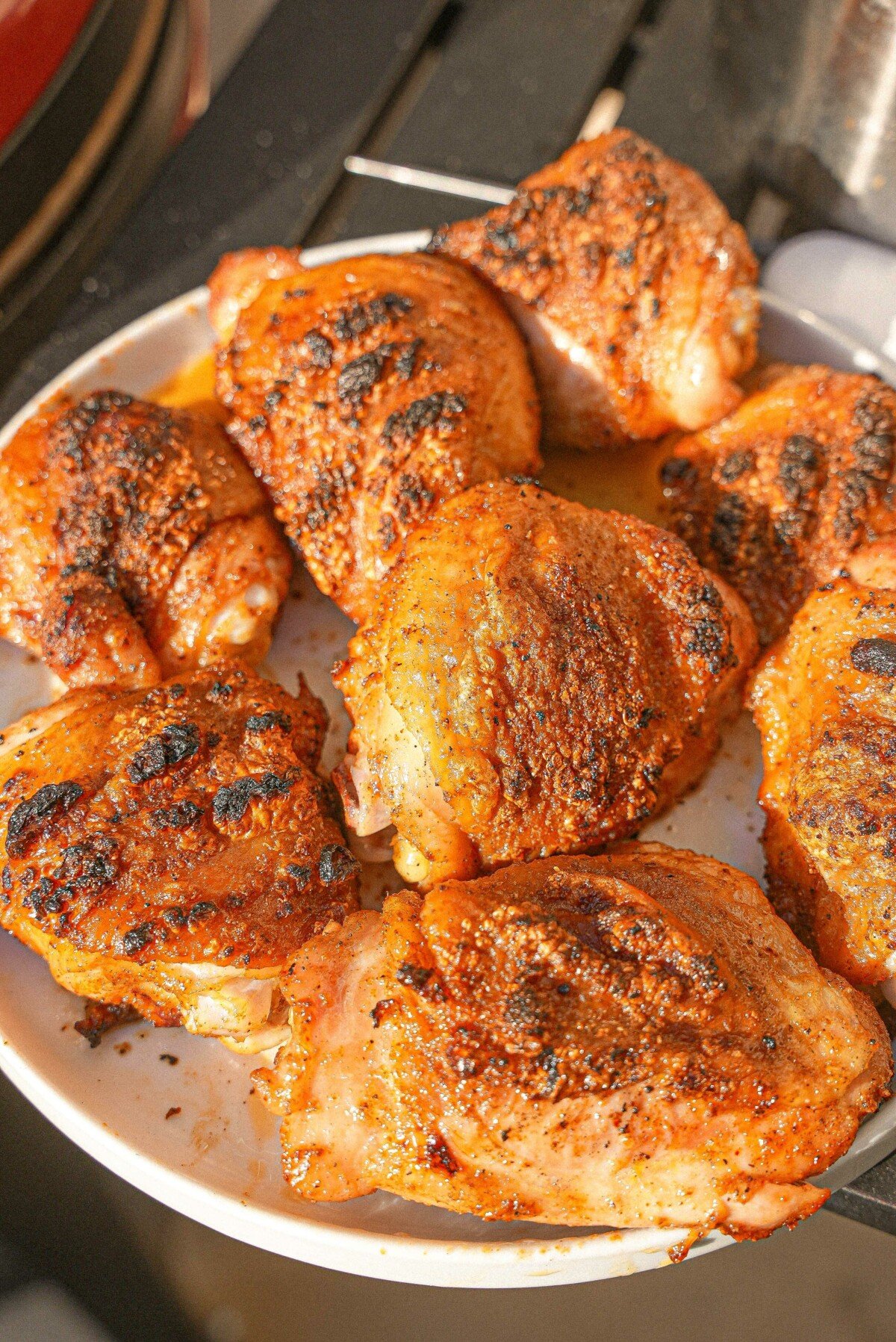 Cooked grilled chicken thighs with crispy skin on a plate.