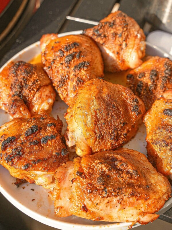 Cooked grilled chicken thighs with crispy skin on a plate.