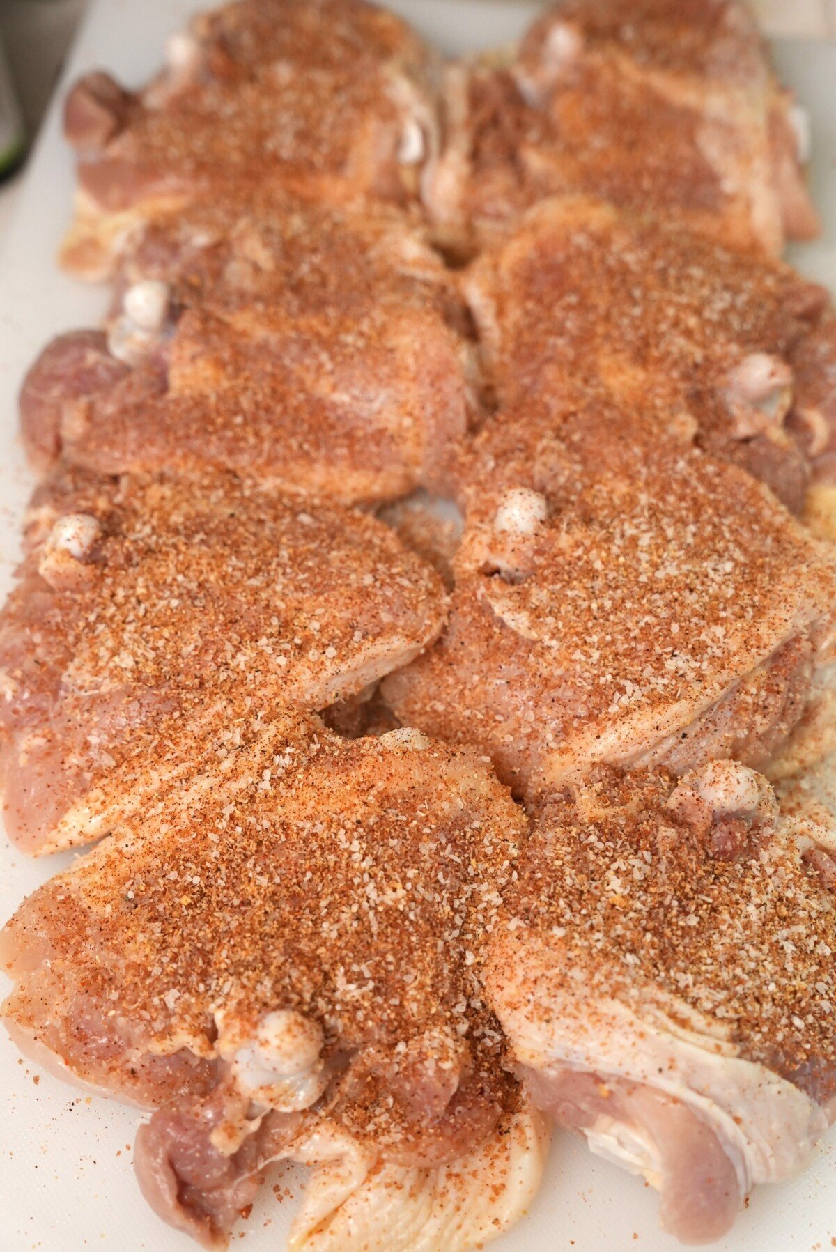 The meat side of the chicken thighs seasoned on a cutting board.