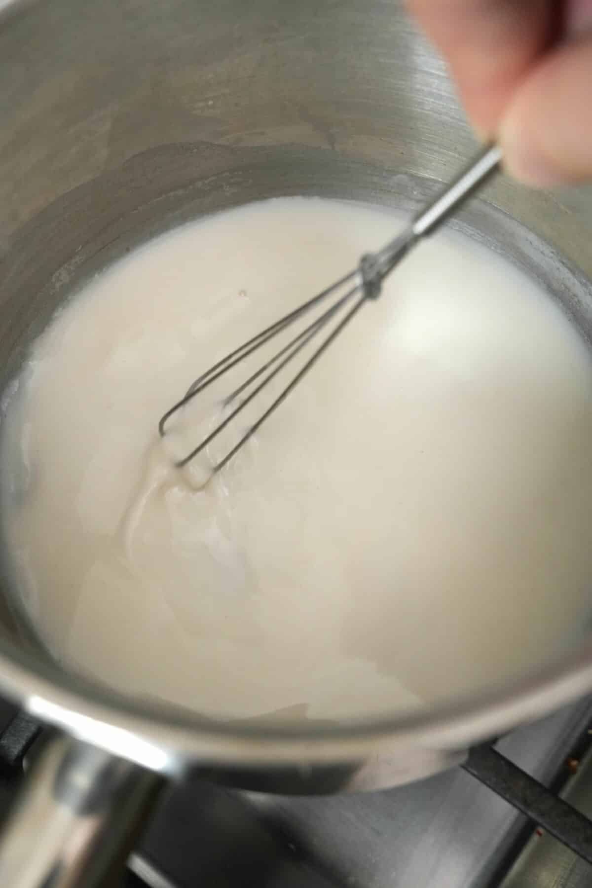 Milk, flour, and water mixing in a pot to make a tangzhong.