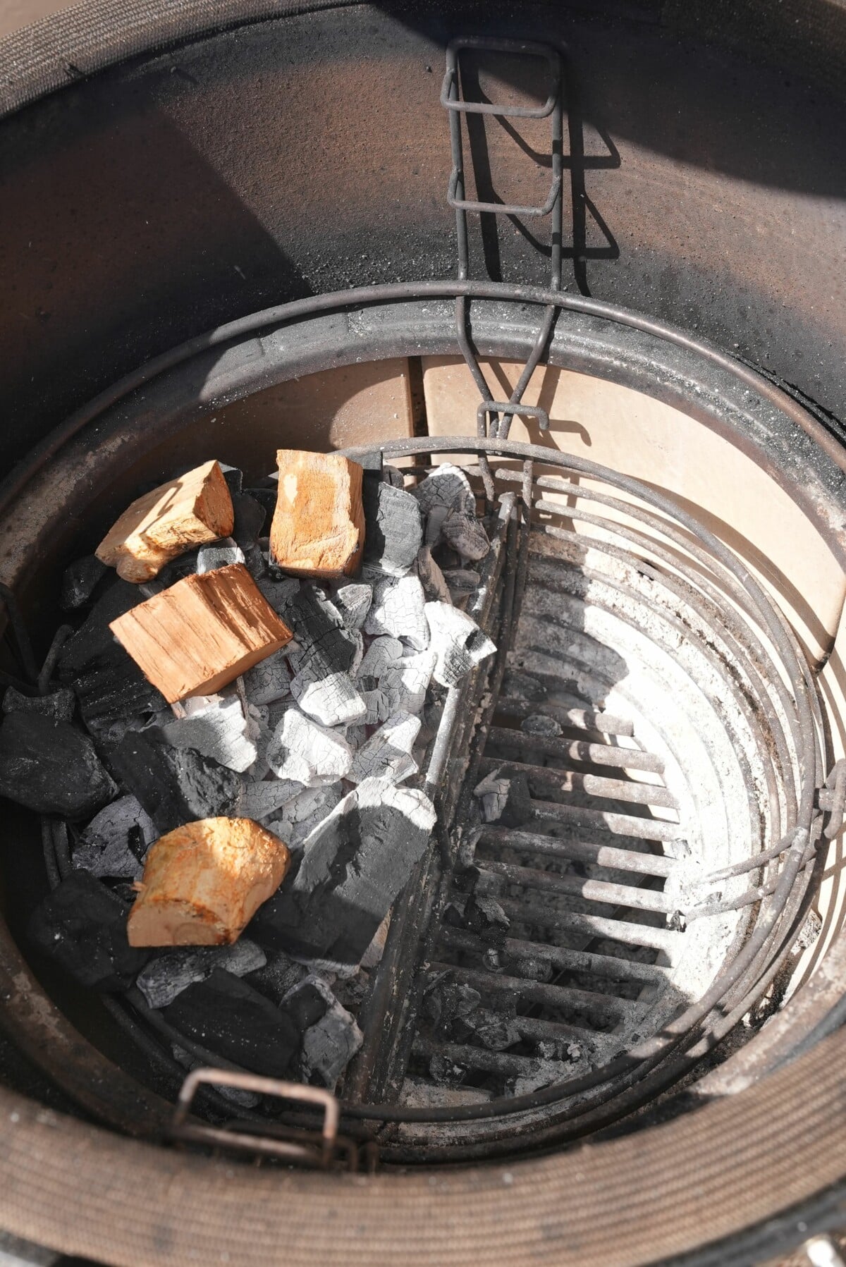 Showing the charcoal and smoking wood on one side of the grill for a direct and indirect setup.