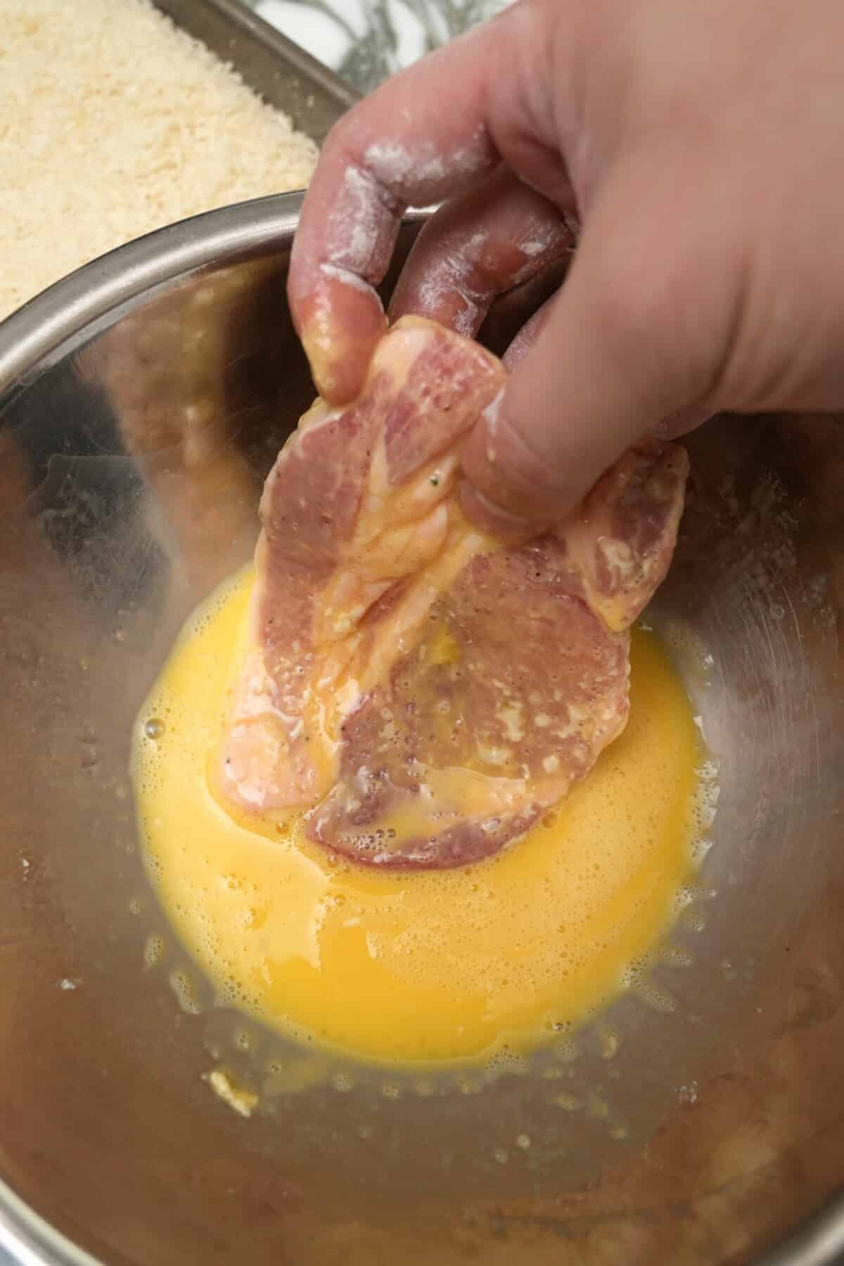 Pork loin being dredged in egg.