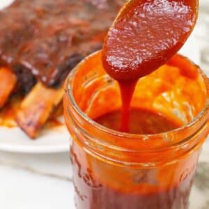Easy homemade BBQ sauce in a jar next to a rack of ribs.