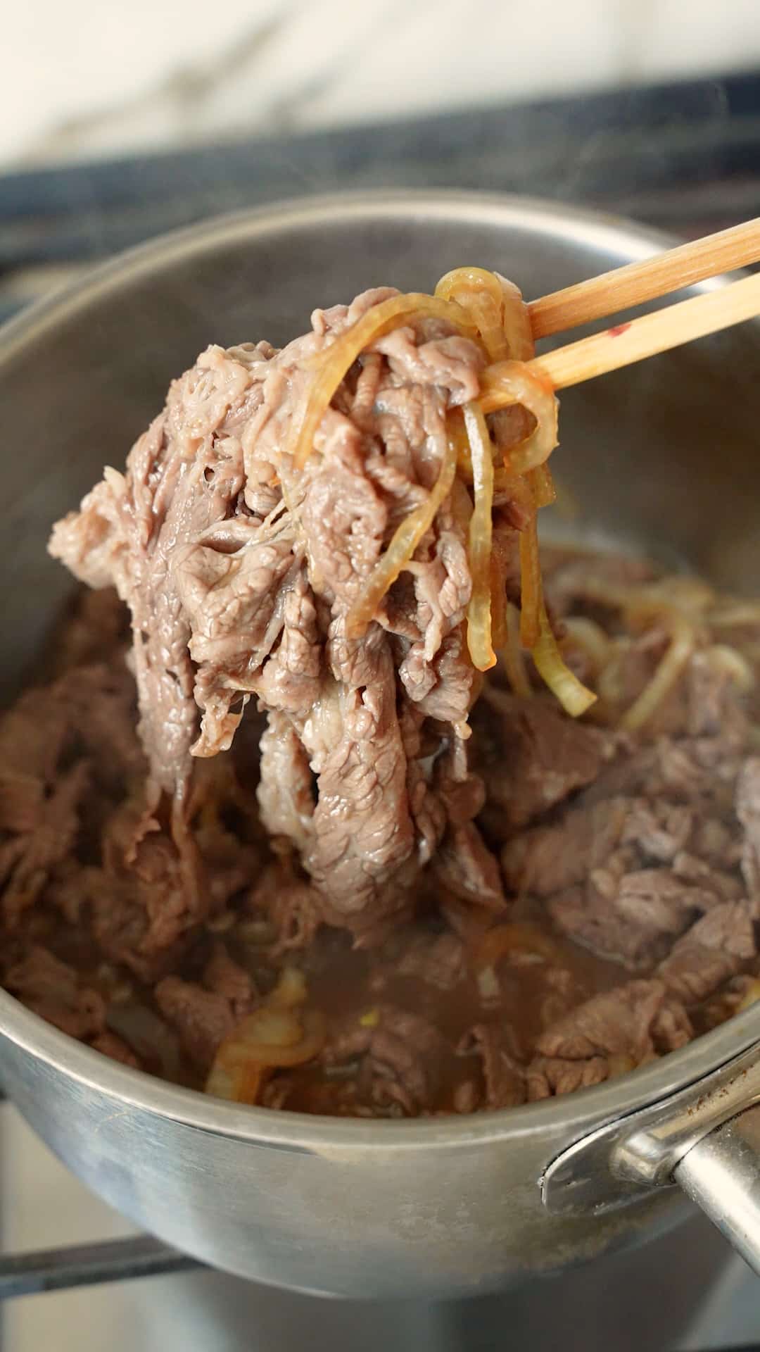 Thinly sliced beef cooked with onions in a pot.