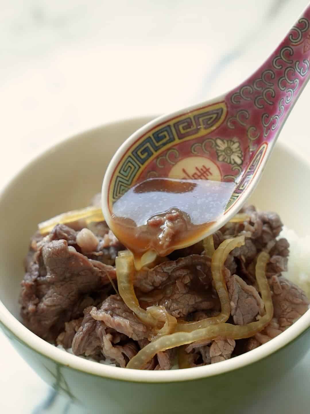 Beef gyudon sauce being topped over beef.