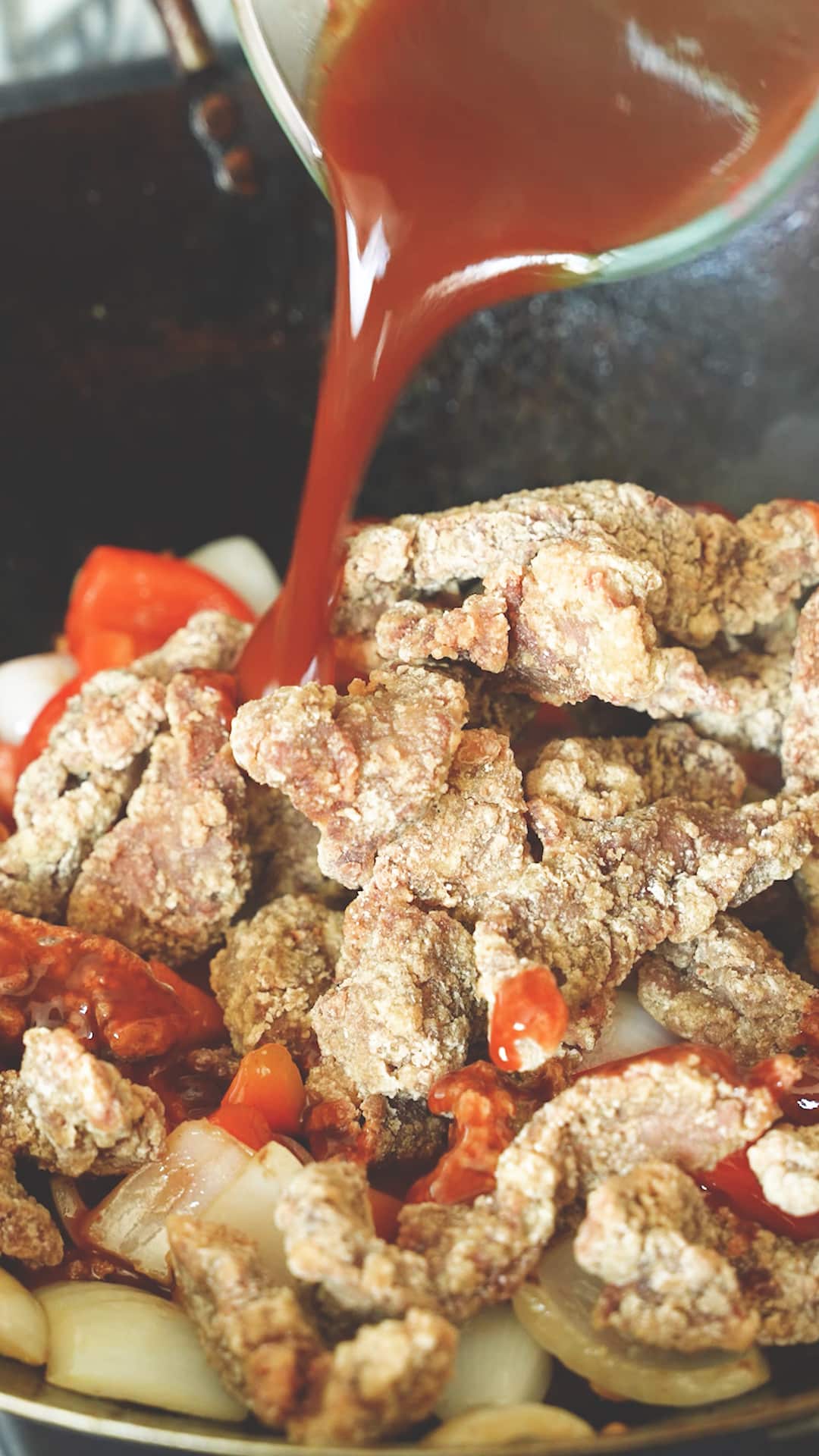 Adding Beijing Beef sauce to the beef, onions, and bell peppers.