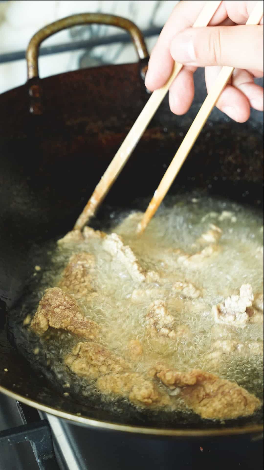 Beef frying in oil in a wok.