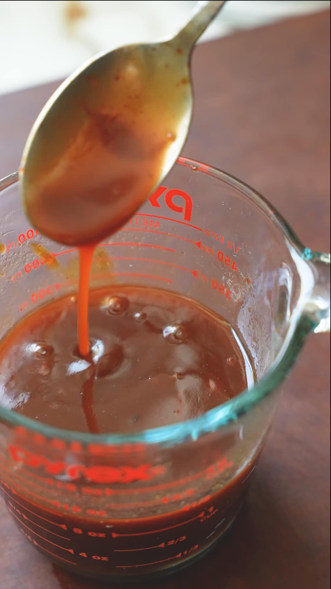 Beijing beef sauce being mixed in a measuring cup with a spoon.