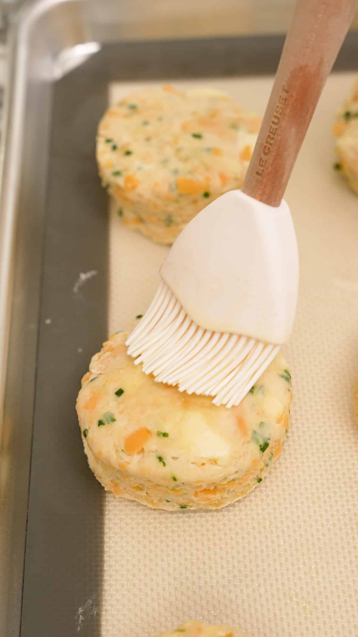 Clarified butter being brushed onto the biscuits on a tray.