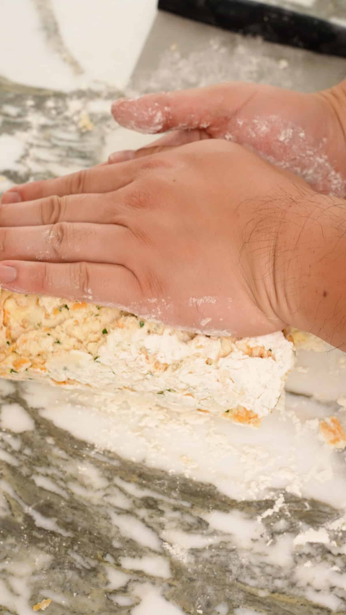 Hands folding the bottom third of the dough onto itself.