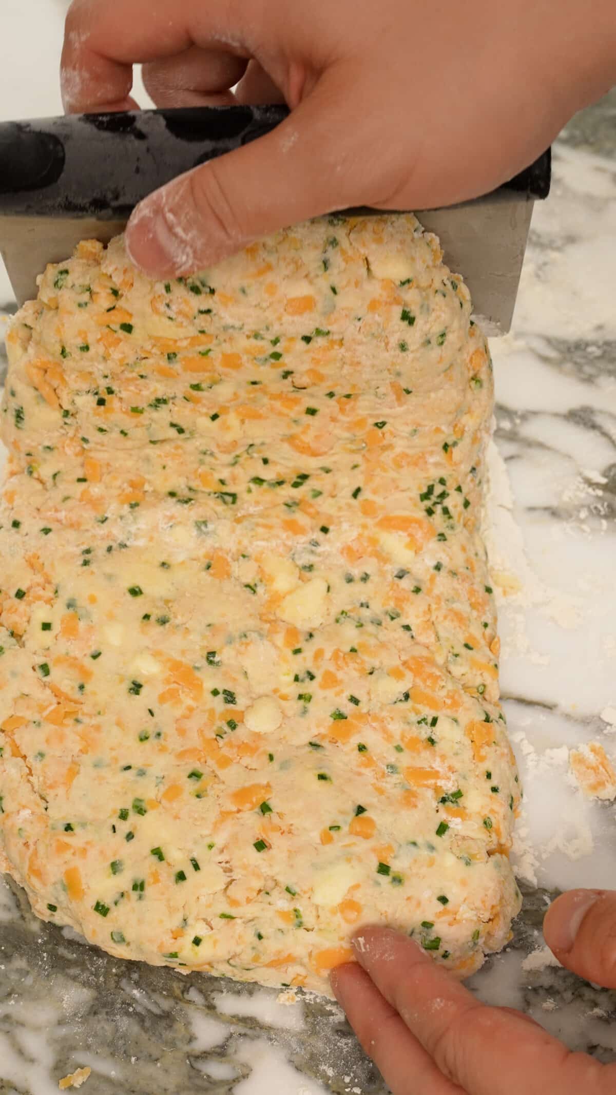 Hands folding the top third of the biscuit dough onto itself.