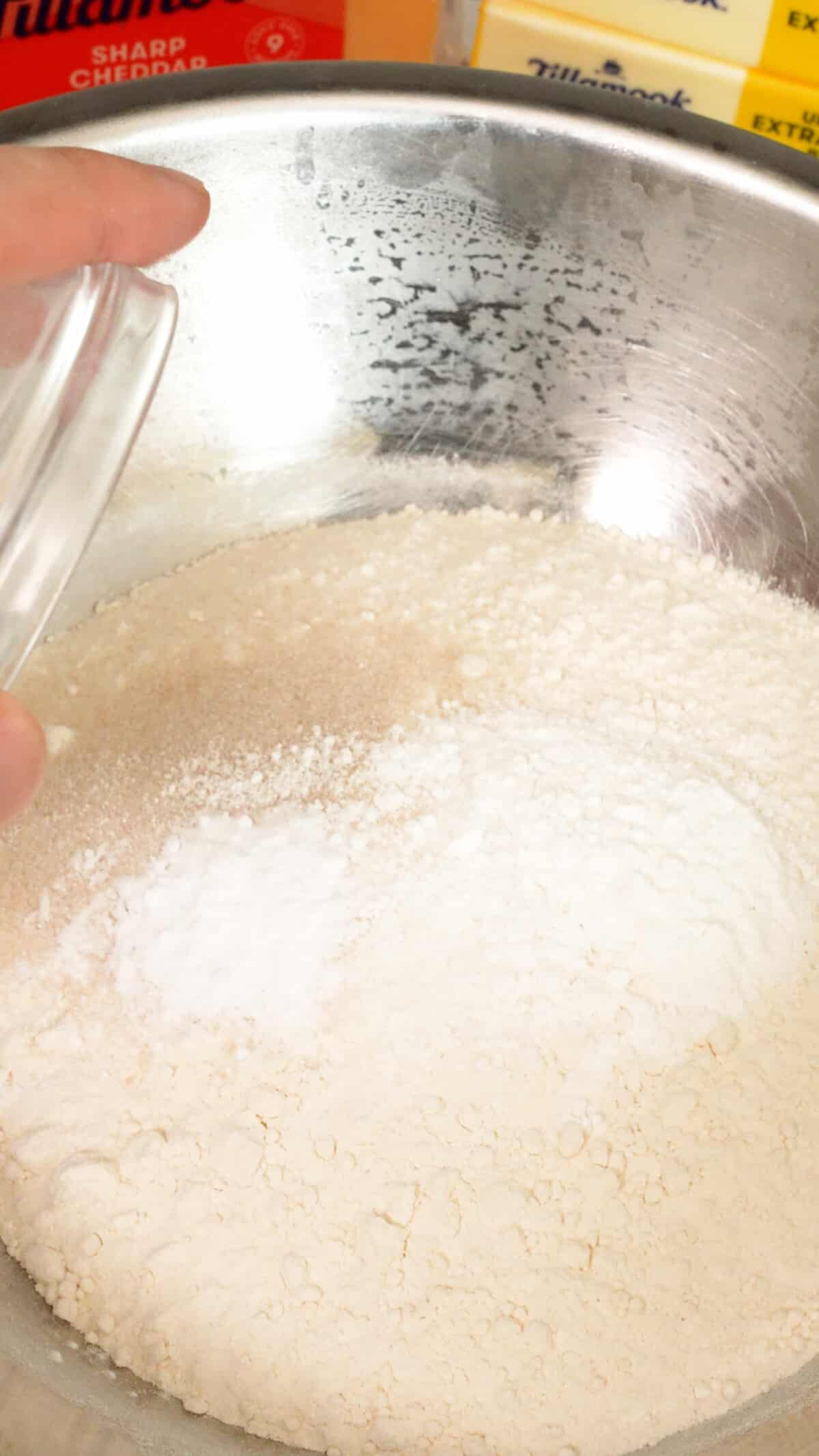 Dry ingredients for biscuit dough being added to a bowl.