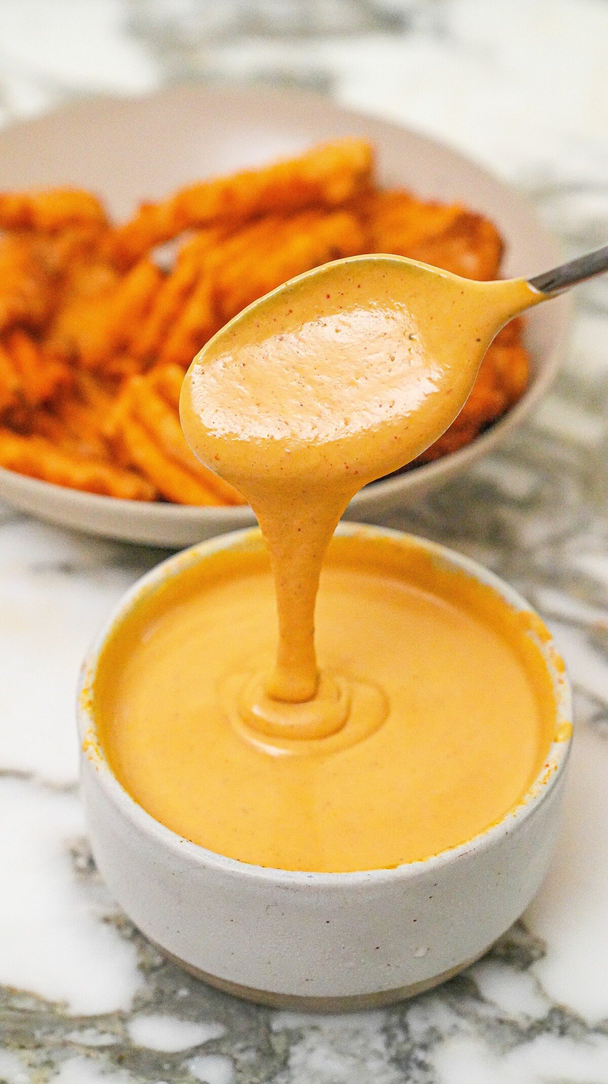 Chick-Fil-A sauce in a bowl in front of a bowl of waffle fries.