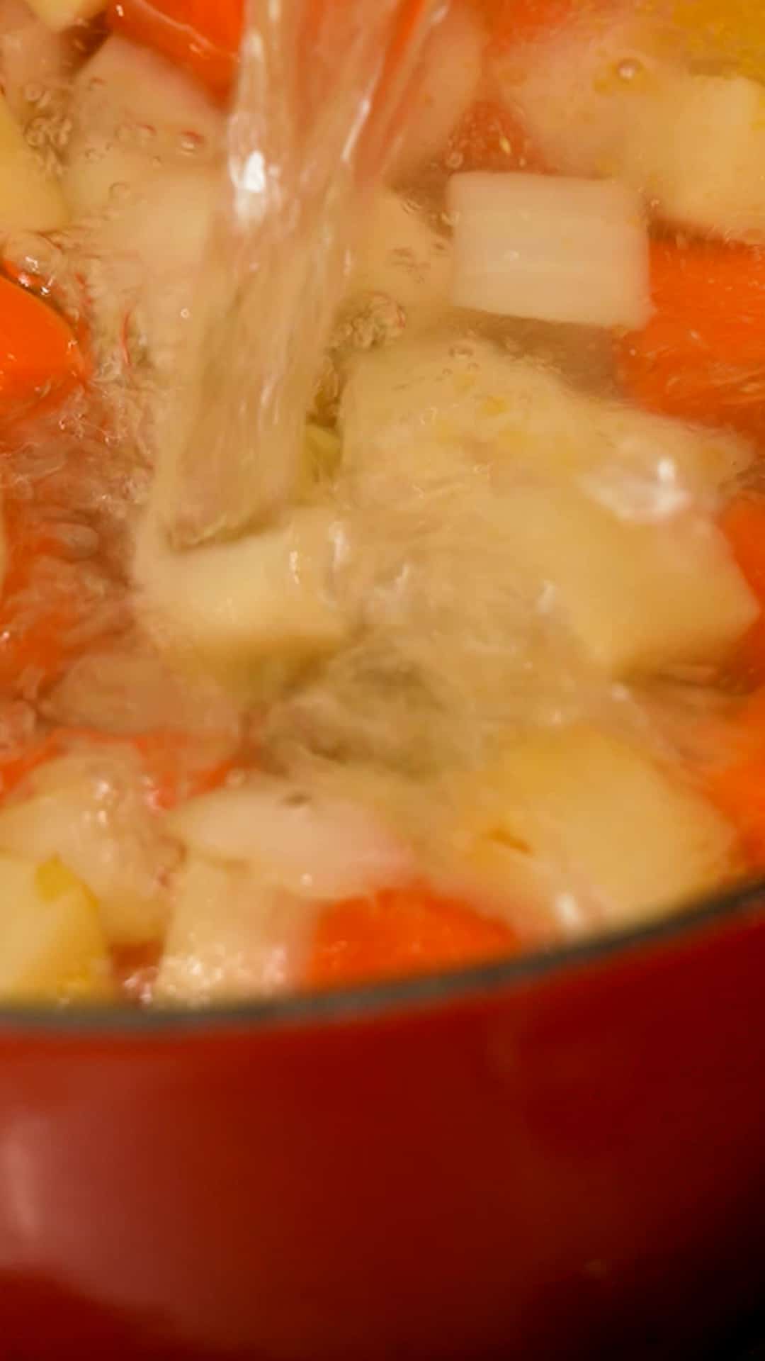 Water being added to vegetables in a dutch oven.