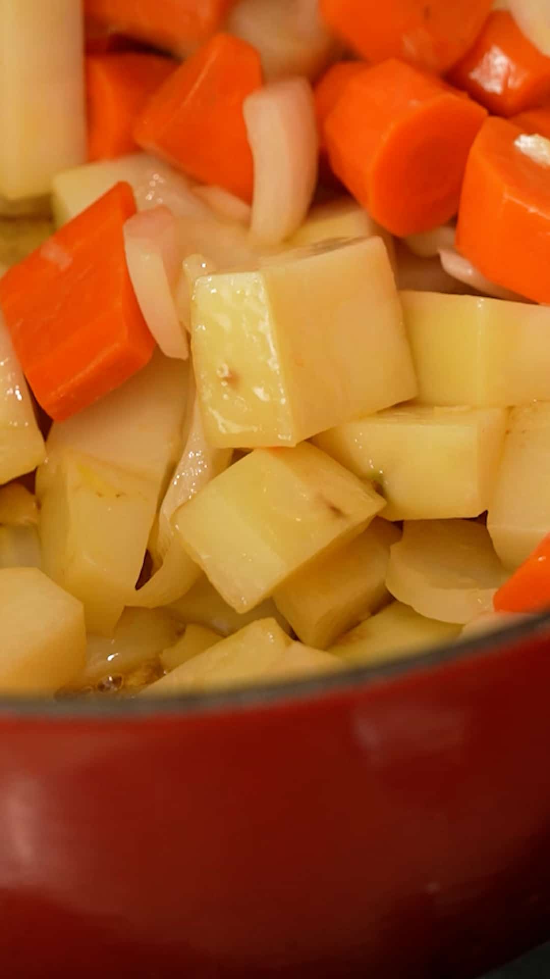 Carrots, onions, and garlic being sauteed in a pot.