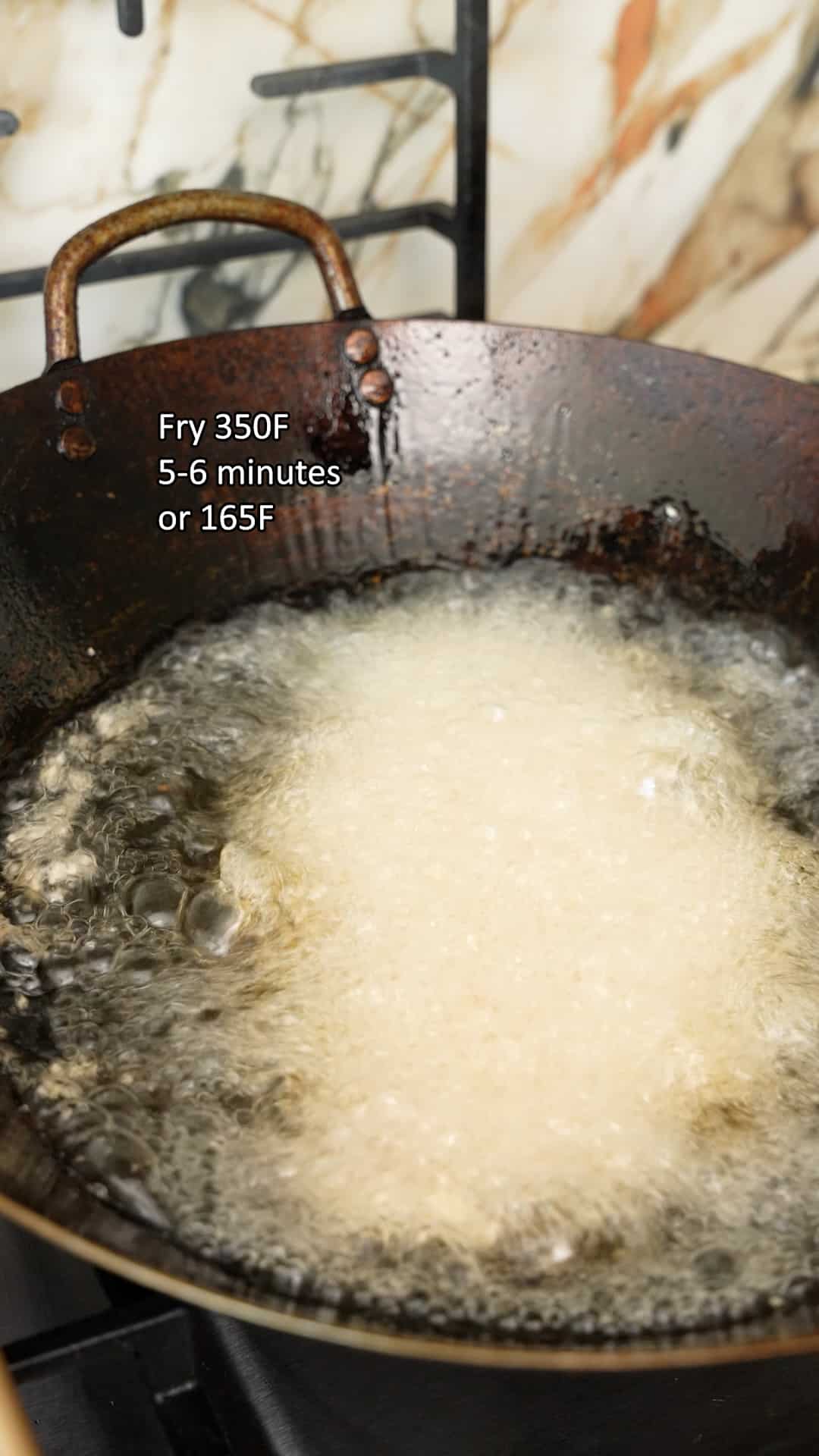 Chicken katsu frying in oil in a wok.