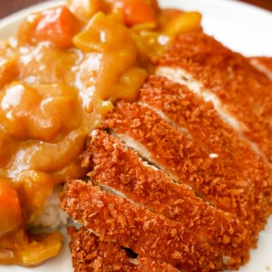 Chicken Katsu with Curry on a bed of rice on a plate.