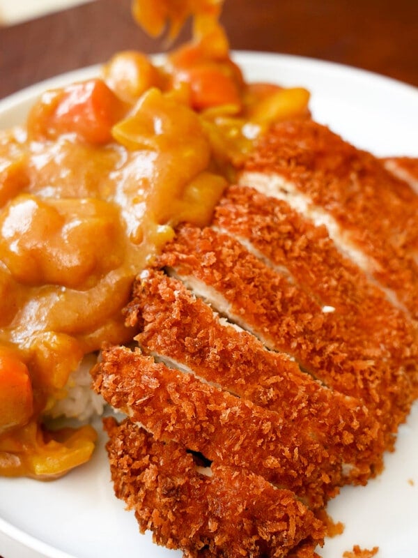 Chicken Katsu with Curry on a bed of rice on a plate.