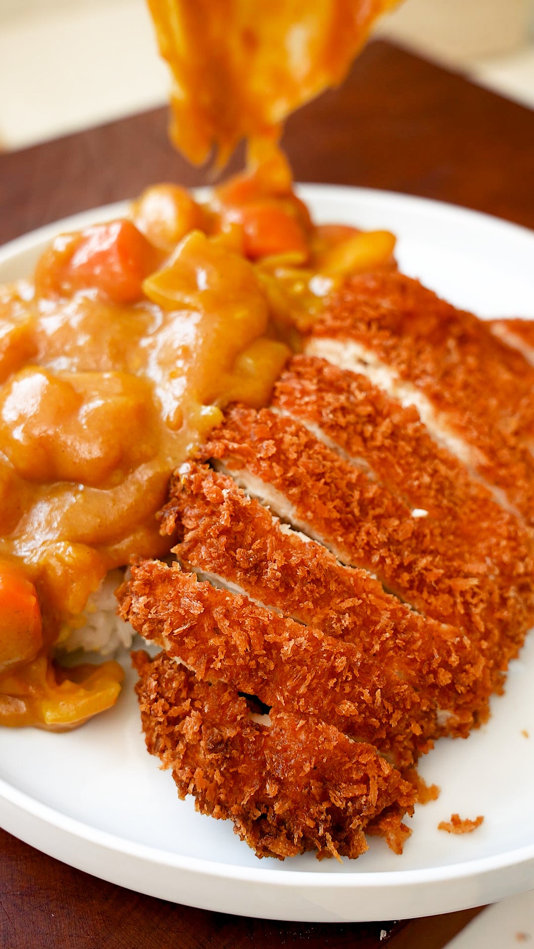 Chicken Katsu with Curry on a bed of rice on a plate.