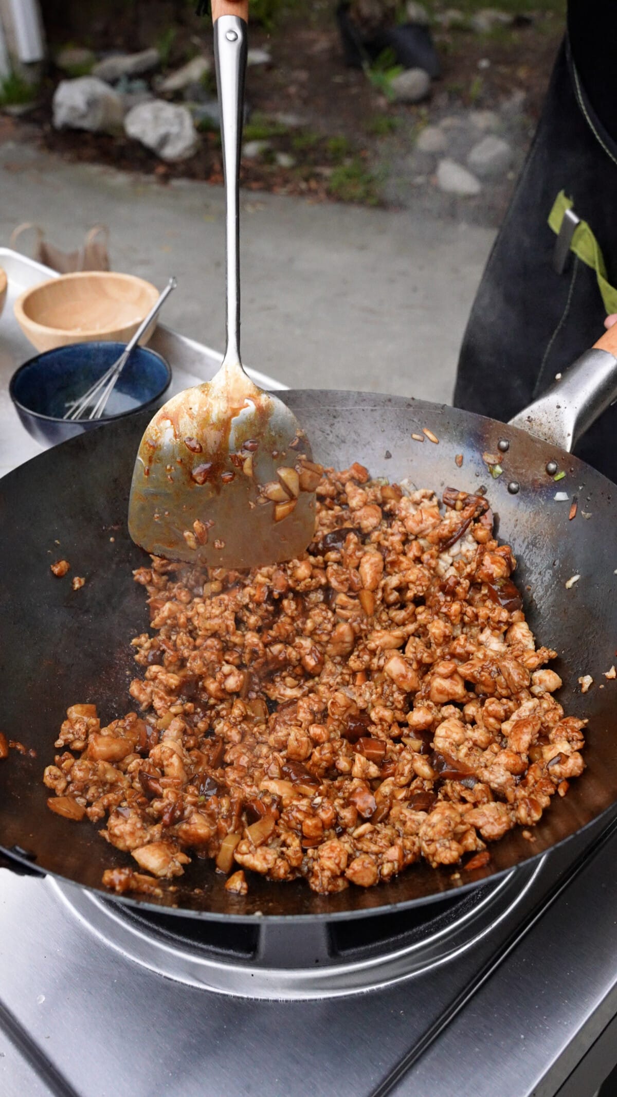 A spatula stirring the chicken lettuce wrap filling in a wok.