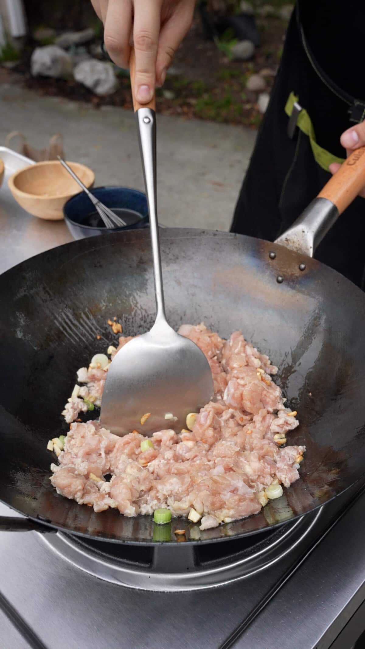 The minced chicken thigh being cooked in the wok with garlic and scallions.