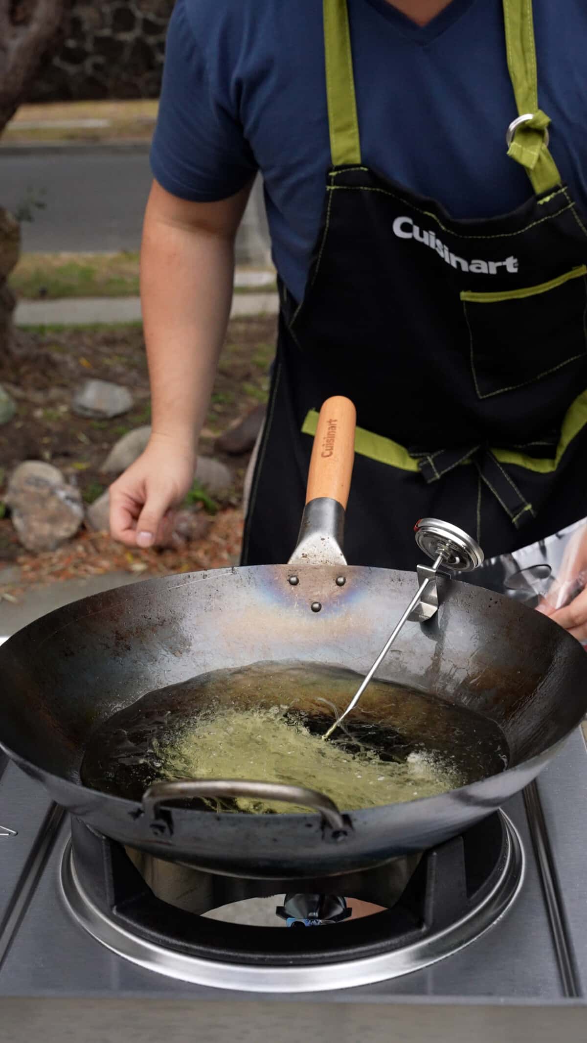 Rice vermicelli noodles being added to hot oil in a wok.