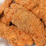 A basket of fried chicken tenders stacked on top of each other.