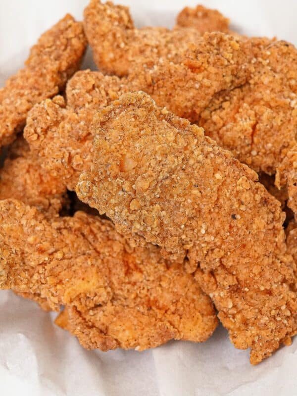 A basket of fried chicken tenders stacked on top of each other.
