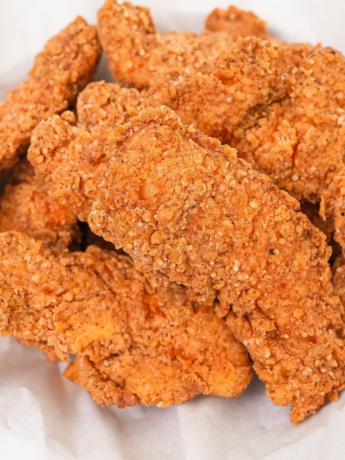 Fried chicken tenders stack on each other in a basket.