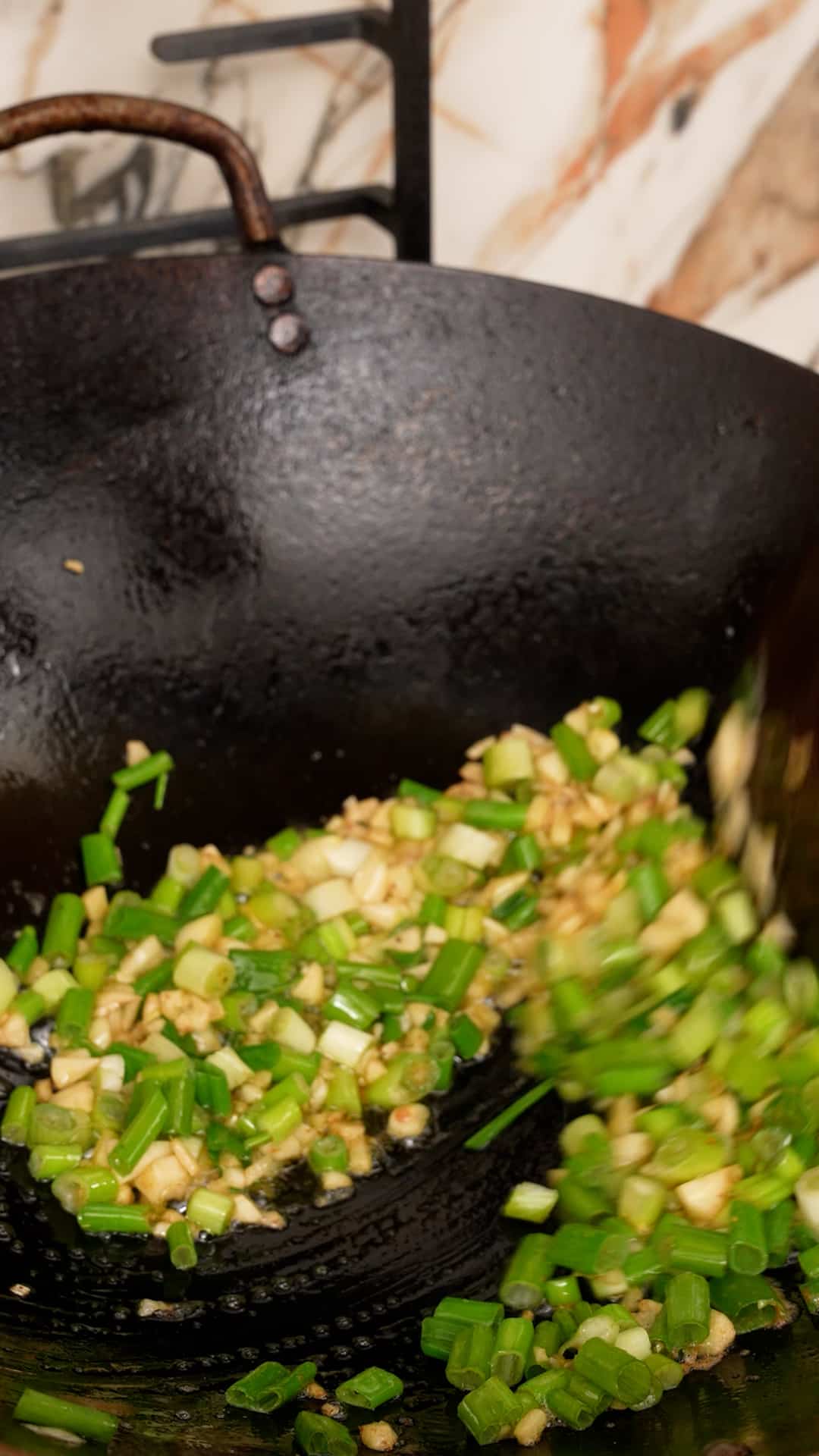 Stir frying scallions and garlic in a wok.