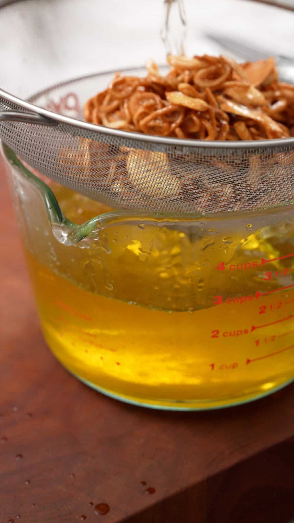 Crispy shallots and garlic strained from oil in a measuring cup.