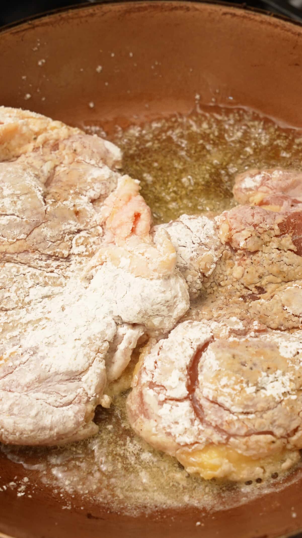 Honey garlic chicken cooking in a pan skin side down.