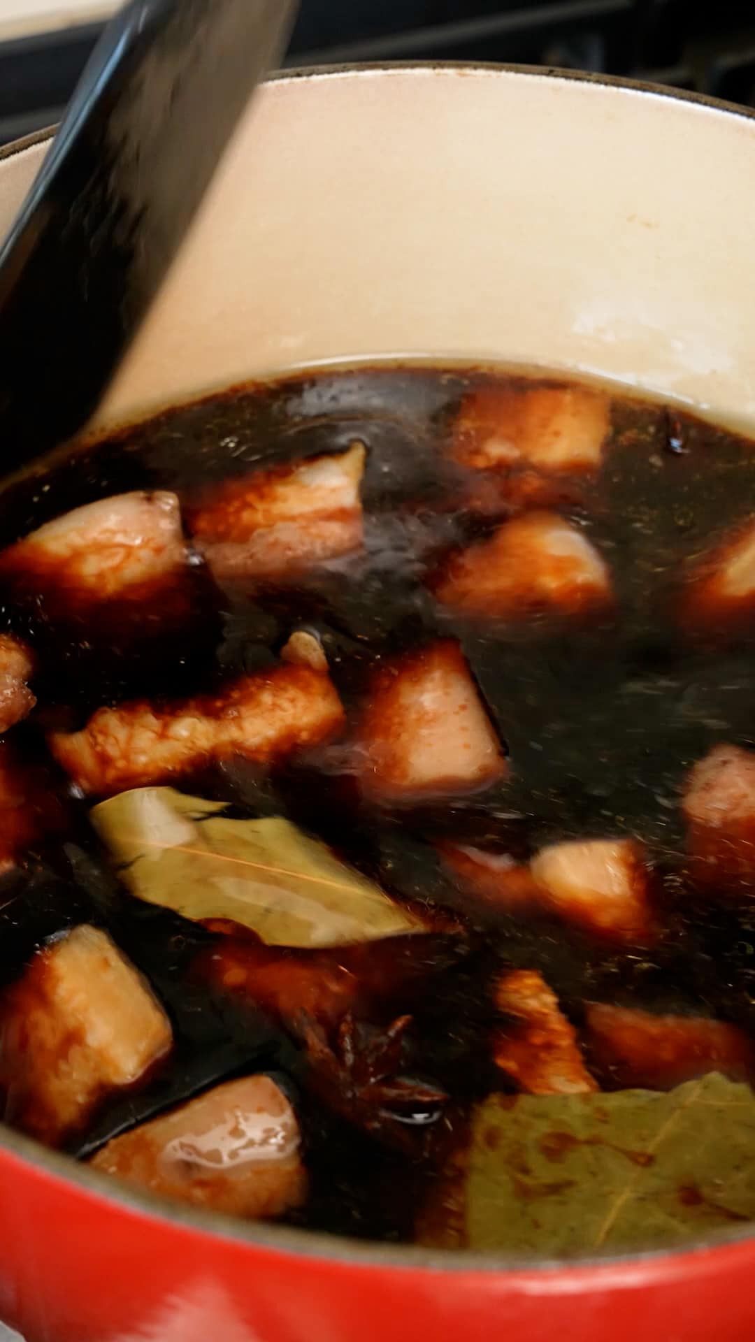 Liquid being added to a pot with pork belly.