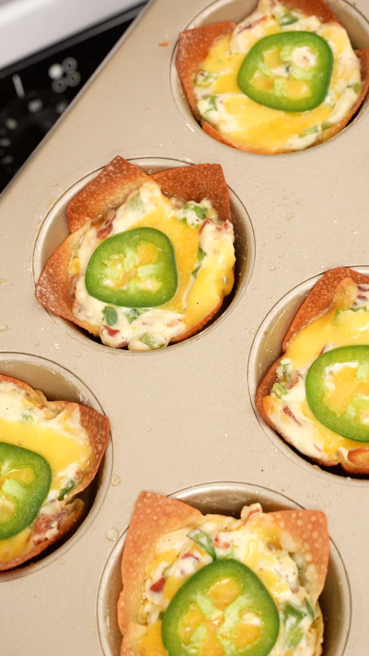 Cooked Jalapeno popper wonton cups in a muffin tin.