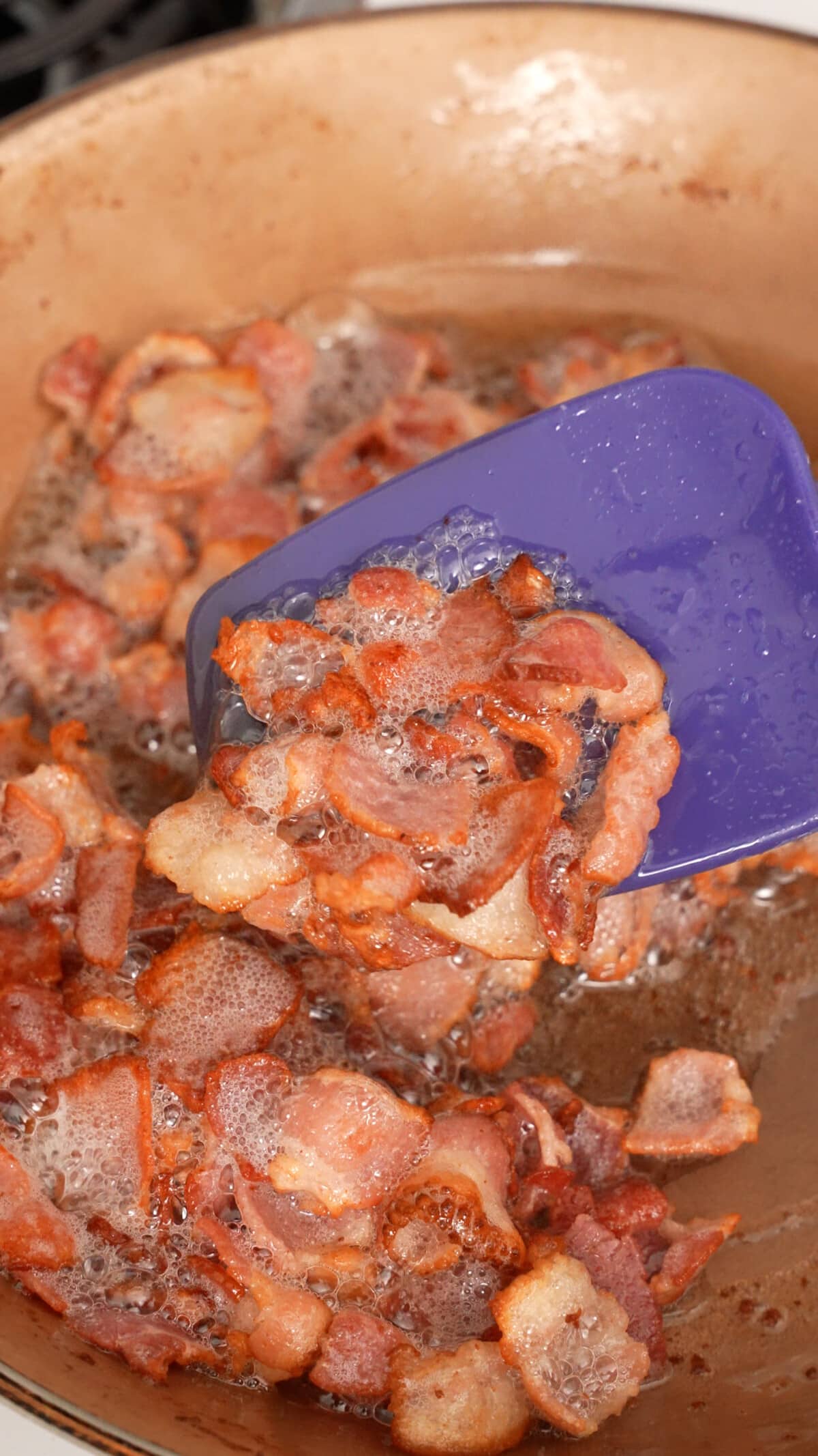 Bacon being fried in a nonstick pan.