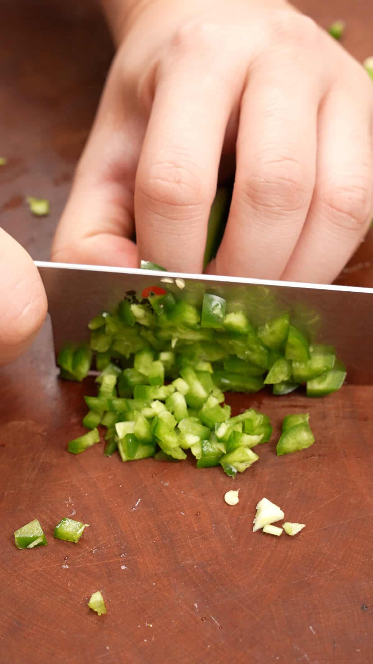 Dicing jalapenos on a cutting board.