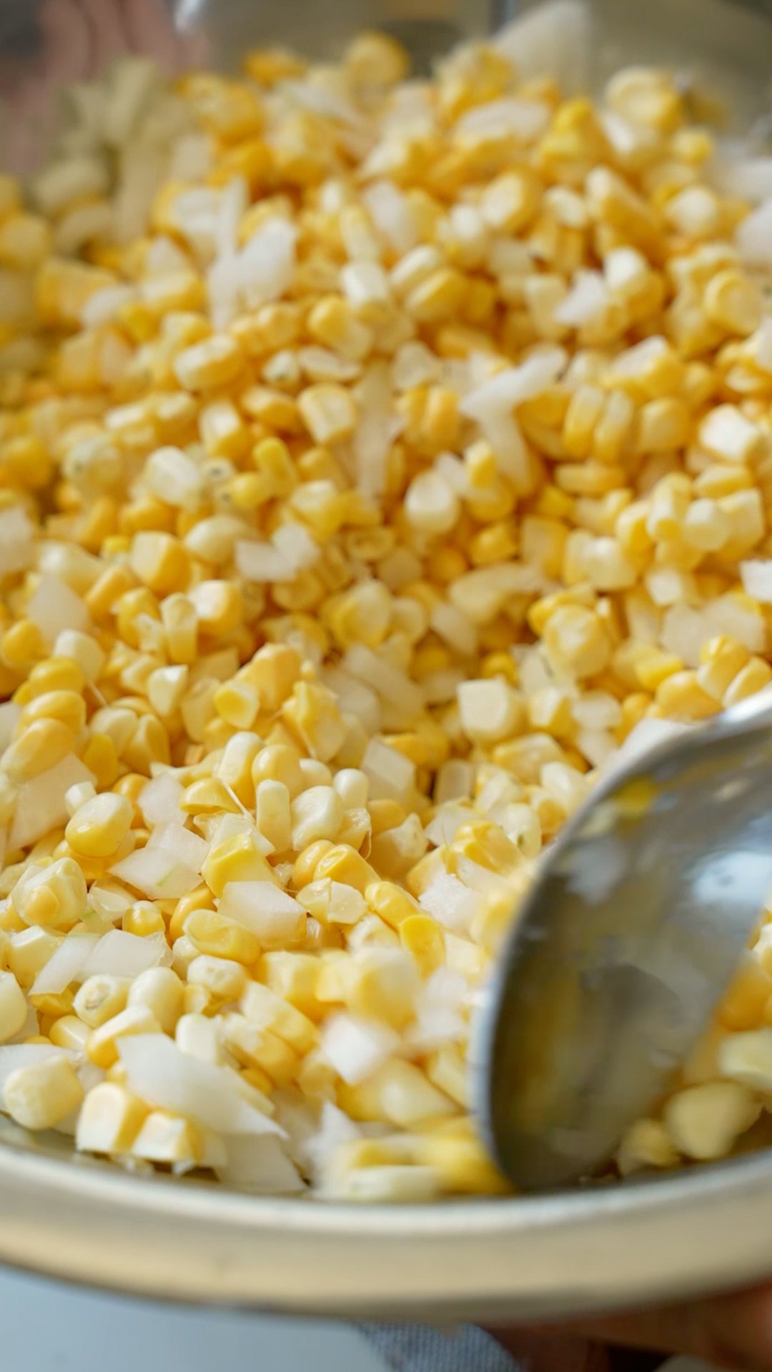 Mixing the corn and onion in a bowl.