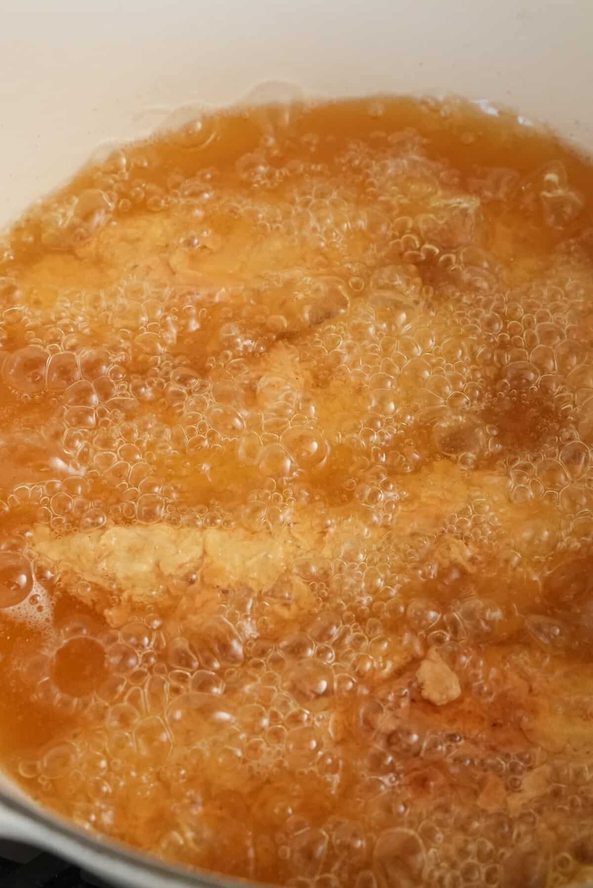 Korean fried chicken frying in a pot of oil.