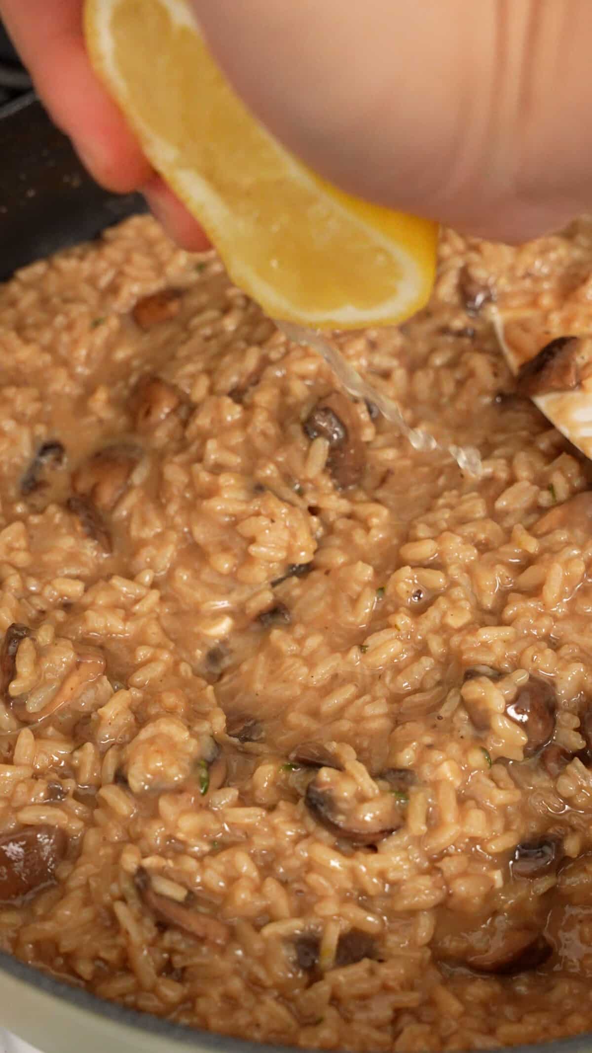 Lemon juice being added to creamy risotto in a pan.