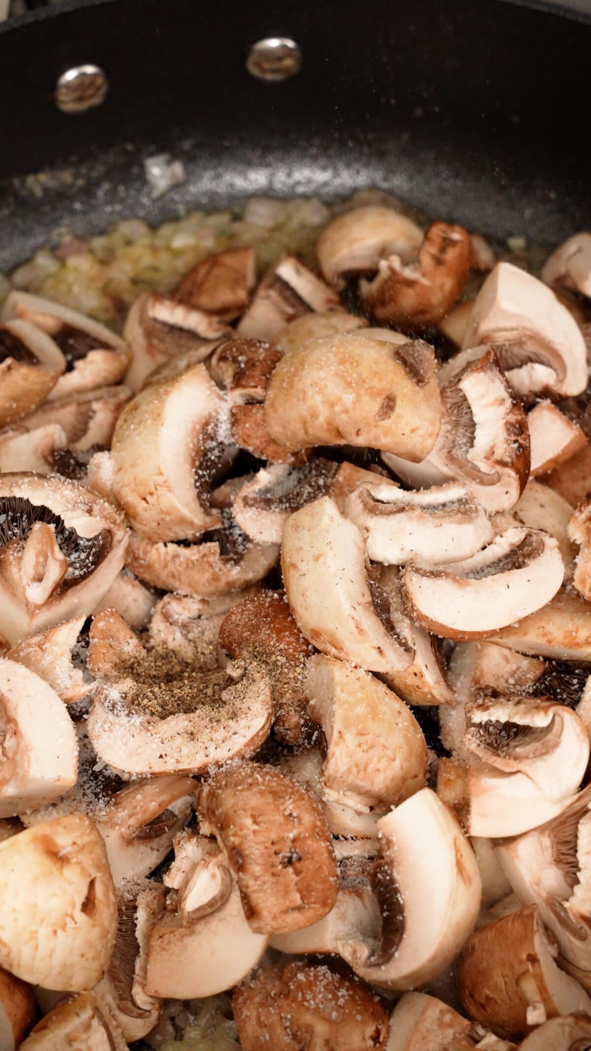 Raw mushrooms seasoned with salt and pepper in a pan.