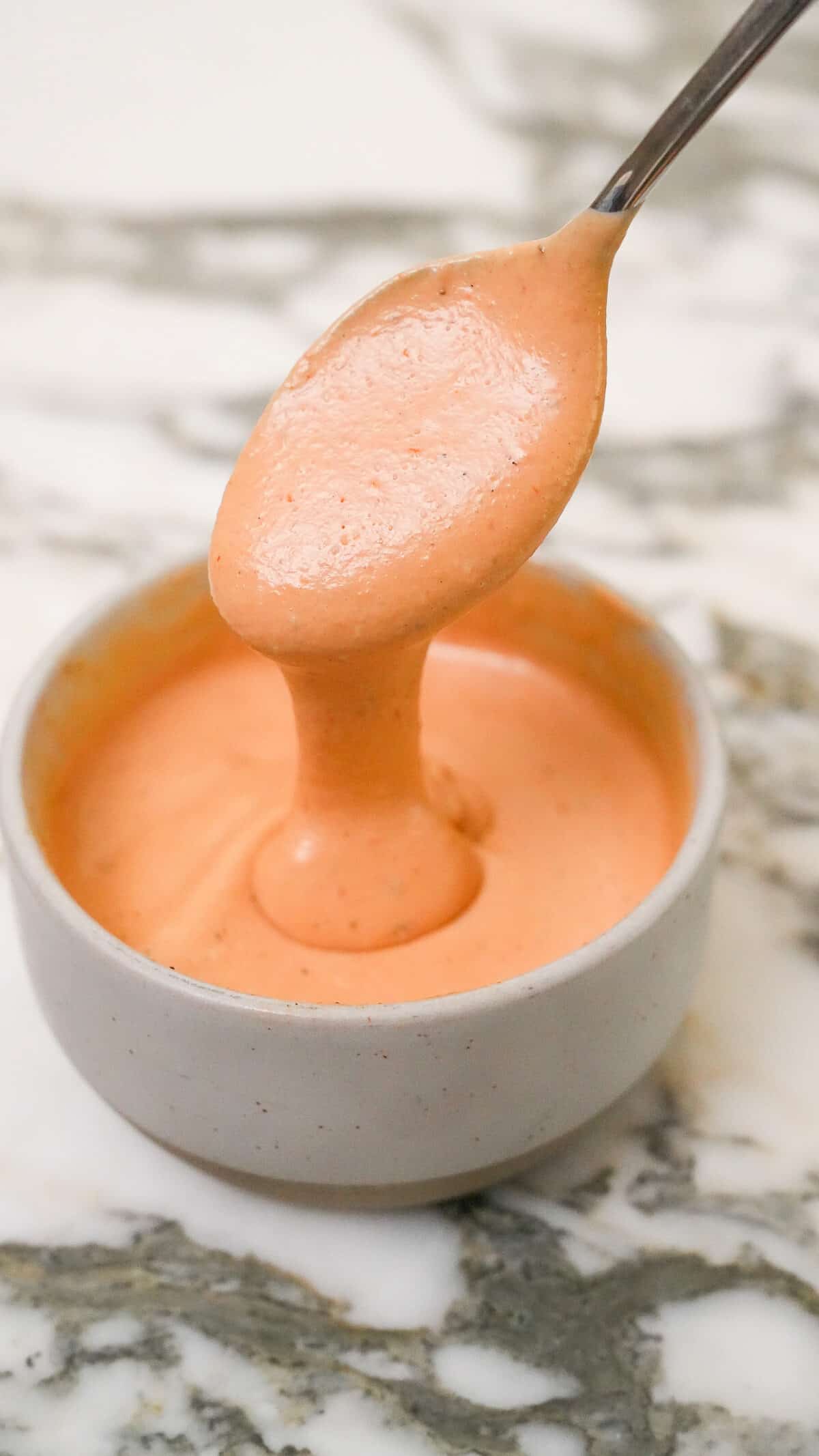 A photo of copycat Raising Cane's sauce in a bowl with a spoon full of sauce.