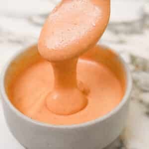 A photo of copycat Raising Cane's sauce in a bowl with a spoon full of sauce.